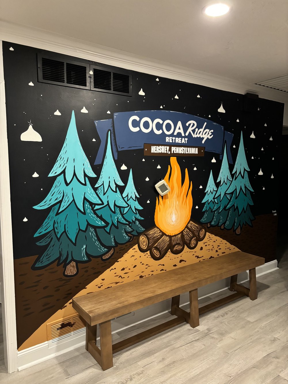 A hand-painted interior mural with pine trees, a campfire, and a playful nod to Hershey Kisses.